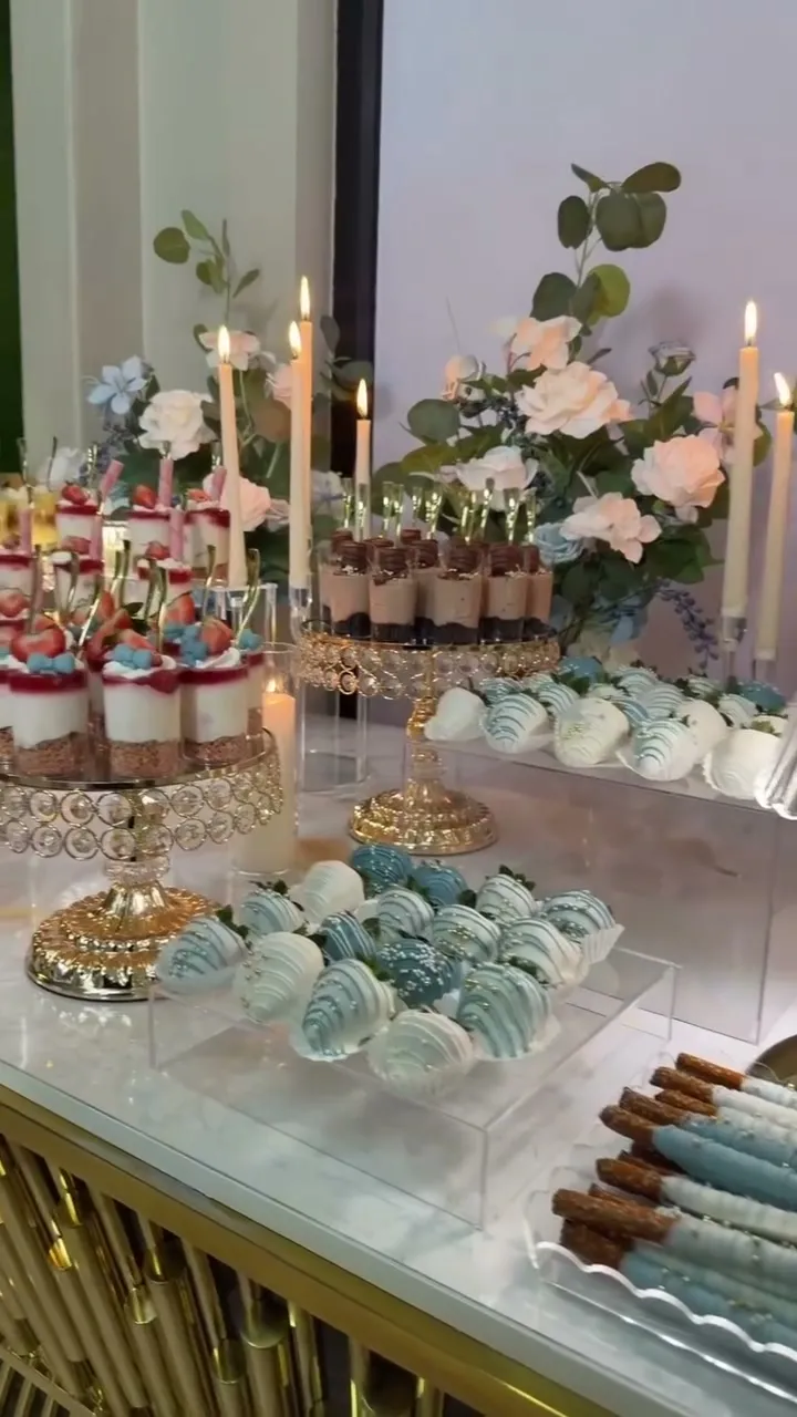 Gold pedestal stands with blue and white dipped strawberries and candles